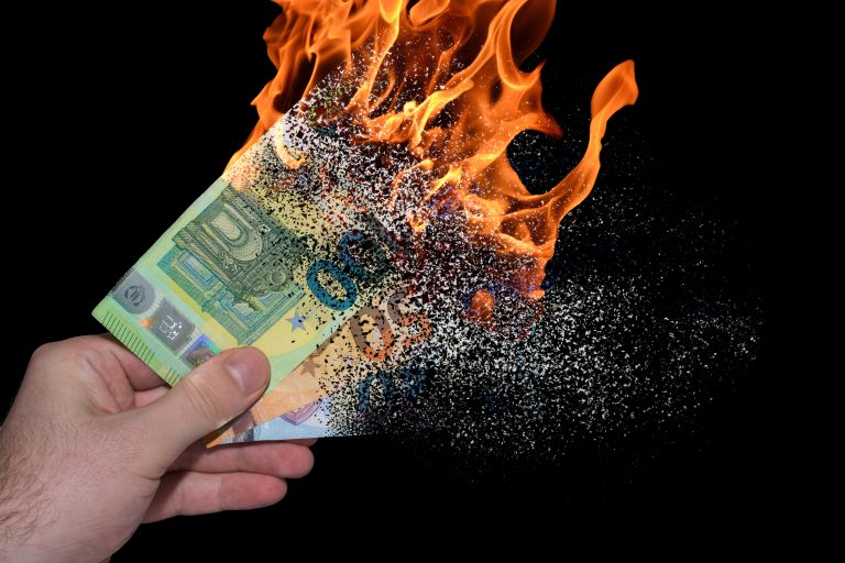 Brennende Euro-Geldscheine in einer Hand vor schwarzem Hintergrund